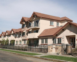 View of Laurel Crest Apartments' exterior showing a series of multi-storied, terracotta-roofed buildings with a secure fence along the sidewalk
