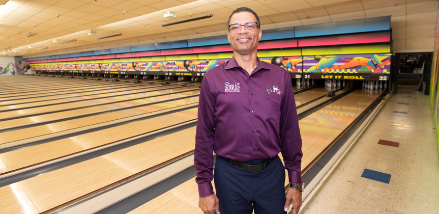 Stacy Anderson standing proudly in the Let it Roll Bowl alley with bowling lanes in the background.