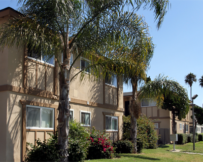 Side view of Oakview affordable housing with well-kept gardens and palm trees
