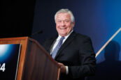 A cheerful man in a suit laughing while speaking at the Clearinghouse CDFI 2024 Annual Shareholders Meeting.