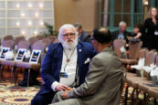 A gentleman with white beard conversing with another attendee at the Clearinghouse CDFI 2024 Annual Shareholders Meeting.