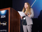 A female speaker presenting at the podium during the Clearinghouse CDFI 2024 Annual Shareholders Meeting