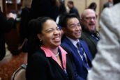 A woman laughing joyously, with two men smiling in the background, at the Clearinghouse CDFI 2024 Annual Shareholders Meeting.