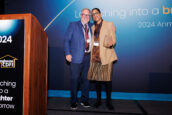 A man and a woman smiling next to a podium at Clearinghouse CDFI's event, the woman holding an award