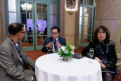 Three professionals engaged in a focused conversation at the Clearinghouse CDFI's 2024 Annual Shareholders Meeting, seated around a round table with a floral centerpiece.