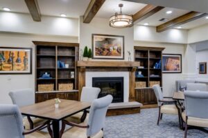 Cozy common area with fireplace, bookshelves, and comfortable seating at WindSong at Southridge Memory Care