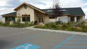 Exterior of the Mono Lake Kootzaduka’a Community Center with a pitched roof, solar panels, native landscaping, and an adjacent parking area.