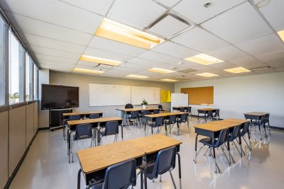 Interior of a classroom with desks, chairs, a whiteboard, and a TV screen, showcasing Clearinghouse CDFI loan partner Red Hook Teach II, LLC
