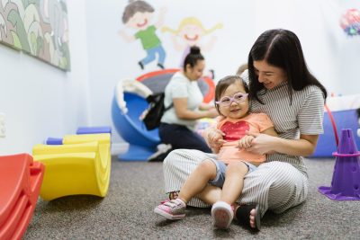 Woman and child sitting on ground smiling at one another, representing the communities Opportunity Zone projects through Clearinghouse CDFI help